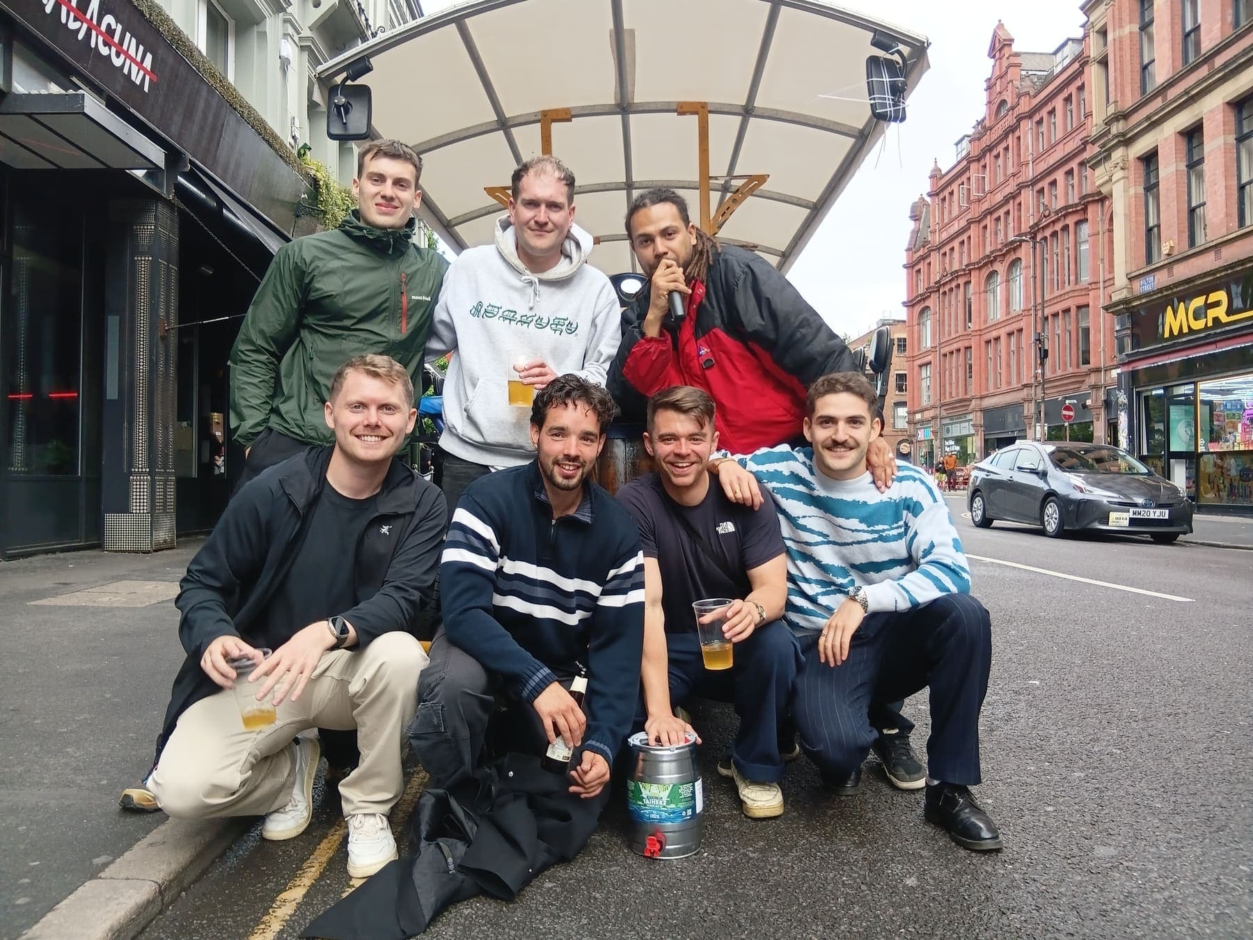 A group of students with drinks beside the PedalCity bike in Manchester